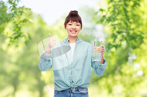 Image of happy asian woman holding glass bottle with water