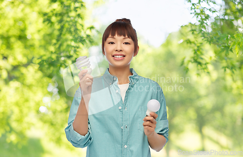 Image of asian woman holding energy saving lighting bulb