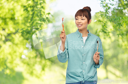 Image of asian woman with wooden and plastic toothbrushes