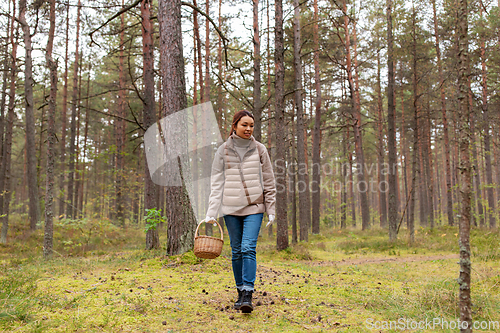 Image of young woman picking mushrooms in autumn forest