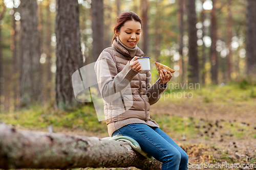 Image of woman drinking tea and eating sandwich in forest