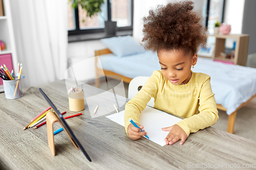 Image of little girl drawing with coloring pencils at home