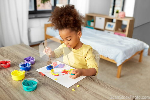 Image of little girl with modeling clay playing at home