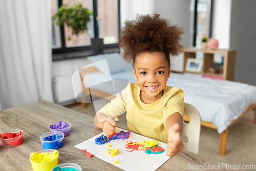 Image of little girl with modeling clay playing at home