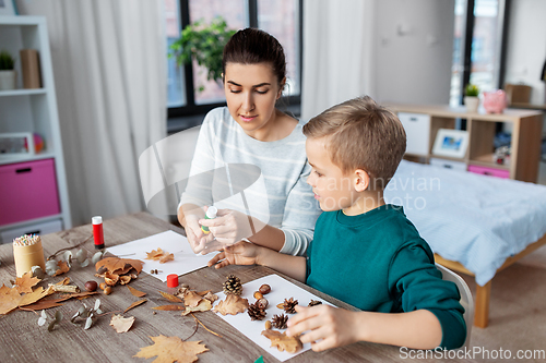 Image of mother and son making pictures of autumn leaves