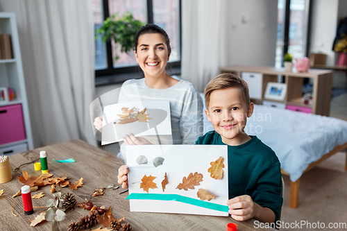 Image of mother and son making pictures of autumn leaves