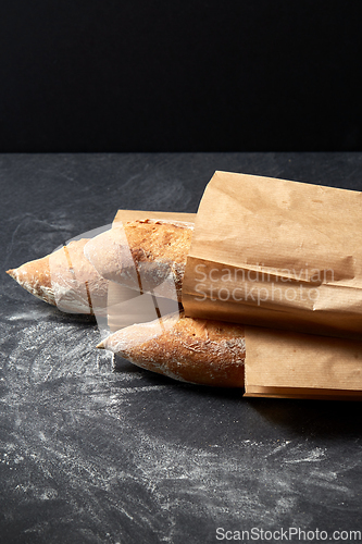 Image of close up of baguette bread in paper bags on table