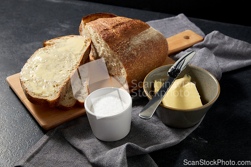 Image of close up of bread, butter, knife and salt on towel
