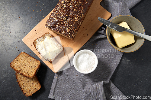 Image of close up of bread, butter, knife and salt on towel