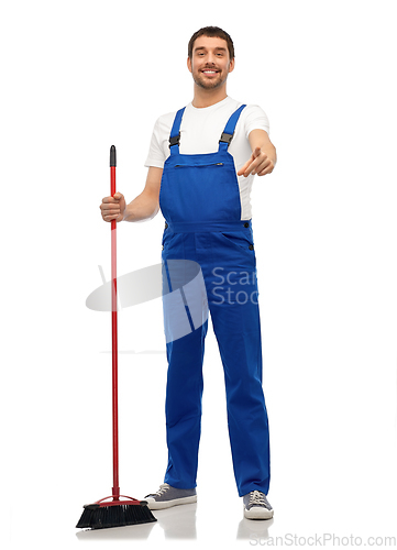 Image of male cleaner in overall cleaning floor with broom