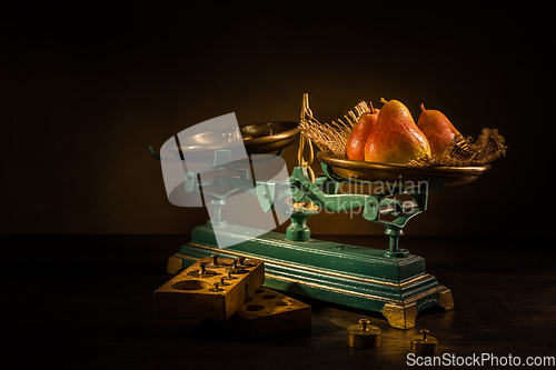 Image of Organic pears on old vintage scales with brass weights on wooden background