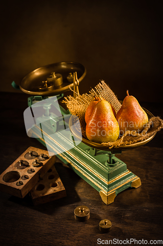 Image of Organic pears on old vintage scales with brass weights on wooden background