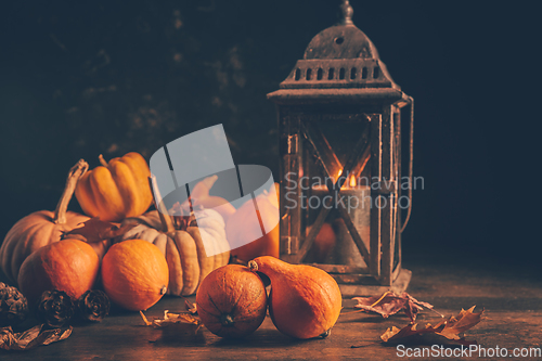 Image of Assortment of pumpkins with autumn leaves on wooden background