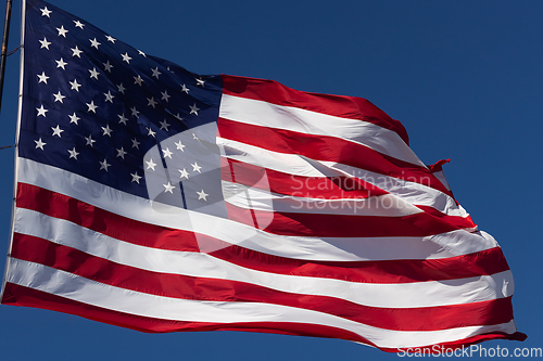 Image of American Flag Waving In Wind Against a Deep Blue Sky