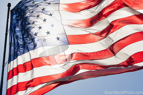 Image of Backlit American Flag Waving In Wind Against a Deep Blue Sky