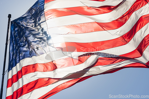 Image of Backlit American Flag Waving In Wind Against a Deep Blue Sky