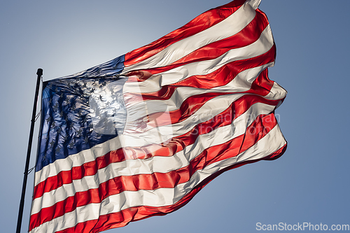 Image of Backlit American Flag Waving In Wind Against a Deep Blue Sky