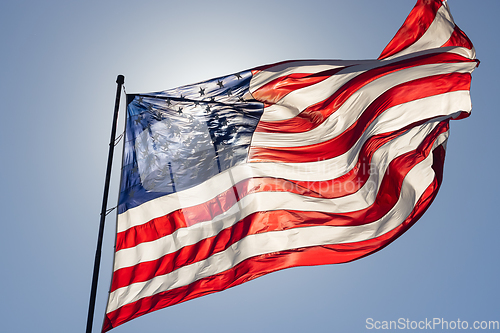 Image of Backlit American Flag Waving In Wind Against a Deep Blue Sky