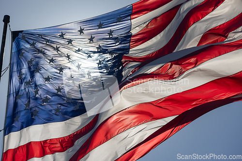 Image of Backlit American Flag Waving In Wind Against a Deep Blue Sky