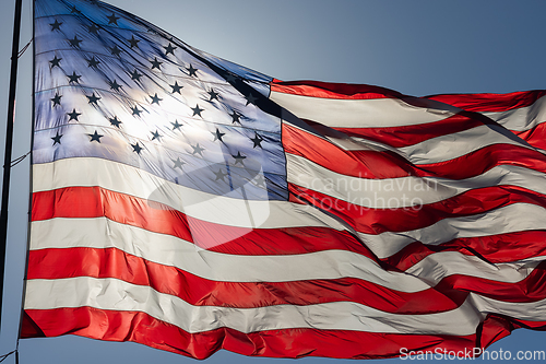 Image of Backlit American Flag Waving In Wind Against a Deep Blue Sky