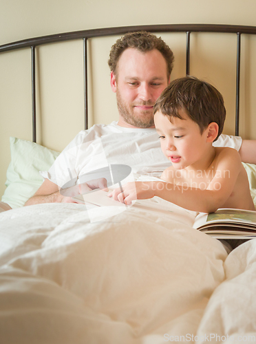 Image of Chinese and Caucasian Baby Boy Reading a Book In Bed with His Da