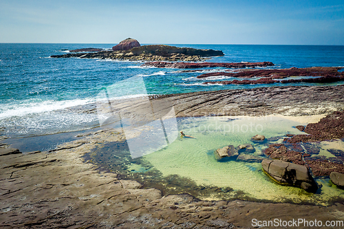 Image of Female in bikini relaxing in ocean rockpools