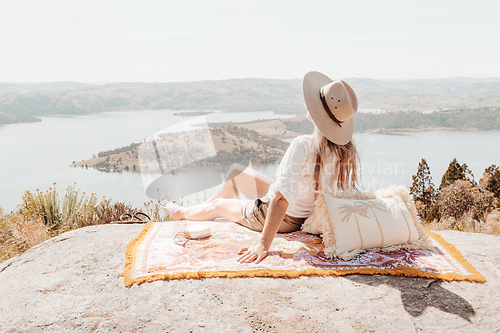 Image of Woman siting high above water views on woven rug