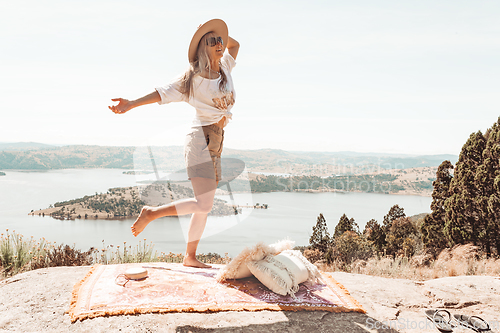 Image of Woman dancing high on a rocky outcrop with views over waterways