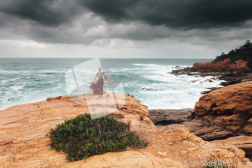 Image of Brave female faces the dark storm by the ocean