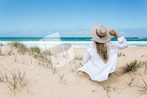 Image of Woman sits on a clean sandy beach in Australia