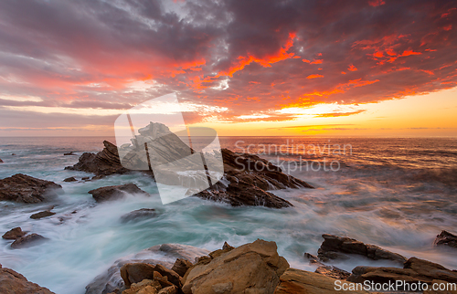 Image of Sunrise over the ocean and rocky beach foreground