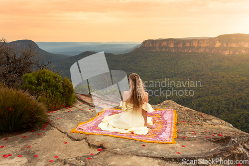 Image of Woman on rug on mountain cliff with vsplendid iews