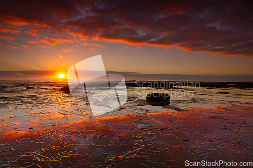 Image of Seaside sunrise and vivid textured rock reflections