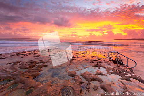 Image of Ocean and rock pool overflow with amazing sunrise sky