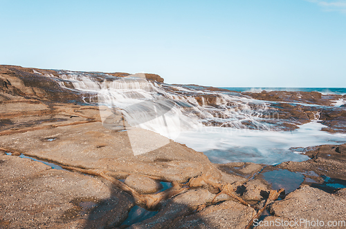 Image of Milky ocean cascades flowing over honey coloured rocks