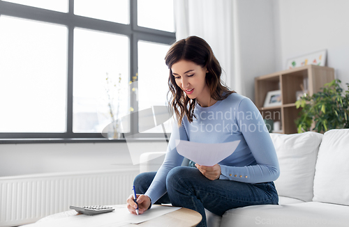 Image of woman with papers and calculator at home