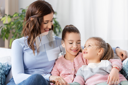 Image of happy smiling mother with two daughters at home