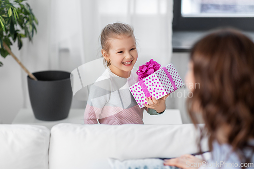 Image of happy daughter giving present to mother at home