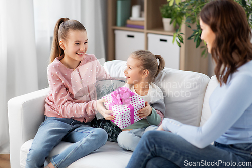 Image of daughters giving present to happy mother