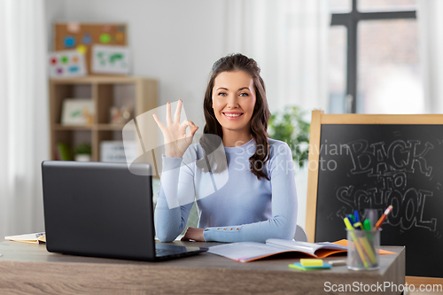 Image of teacher with laptop and notebook working from home