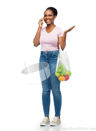 Image of woman with food in net bag calling on smartphone