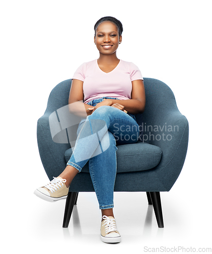 Image of smiling african american woman sitting in armchair