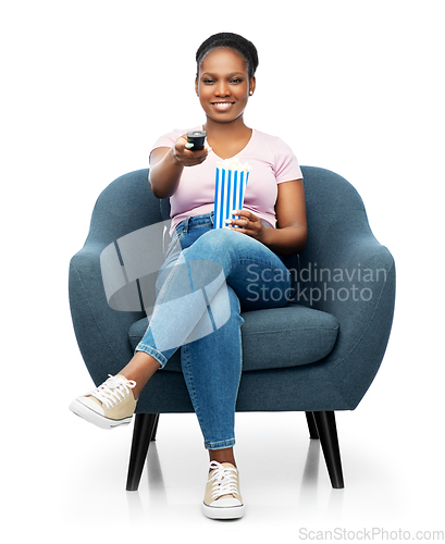 Image of african woman eating popcorn sitting in armchair