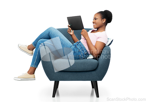 Image of smiling woman with tablet pc sitting in armchair