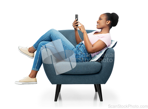 Image of african american woman with smartphone in armchair