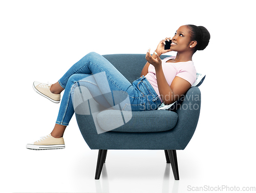 Image of african woman calling on smartphone in armchair