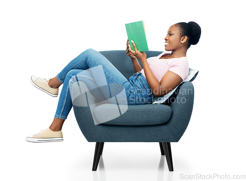 Image of happy young woman in armchair reading book