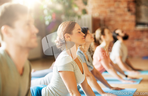 Image of group of people doing yoga cobra pose at studio