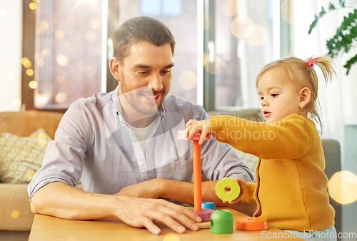 Image of father playing with little baby daughter at home