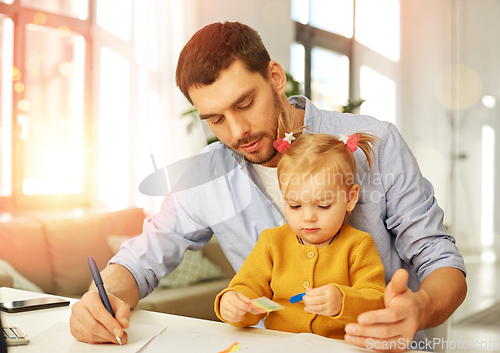 Image of working father with baby daughter at home office